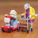 TOBAR aufziehbare Dekofigur Seniorenpaar mit Gehwagen & Scooter Bild 2