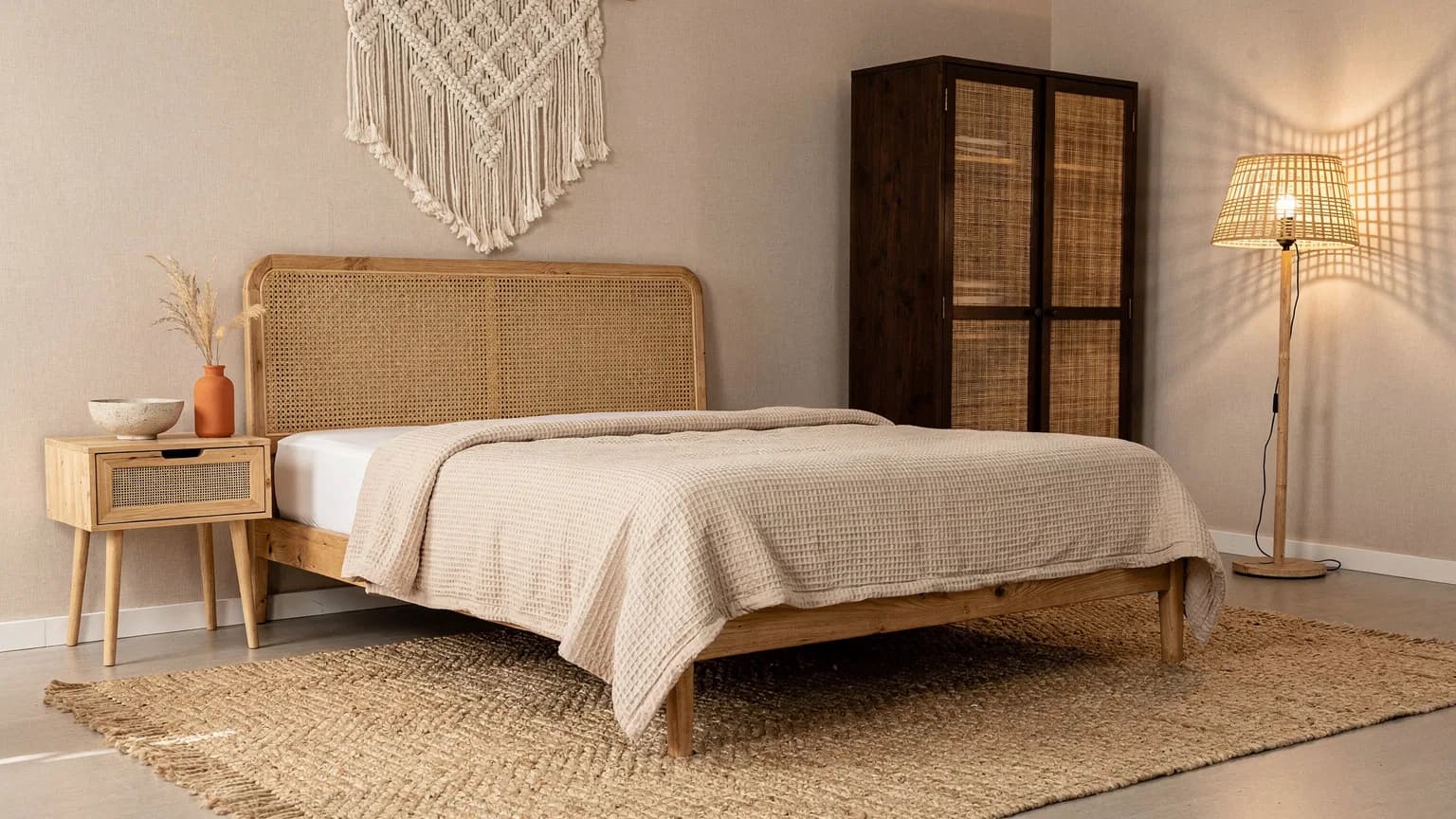 Boho Schlafzimmer mit Eichenbett und Rattan-Kopfteil, Juteteppich, Makramee-Wandbehang und leuchtender Bambus-Stehlampe