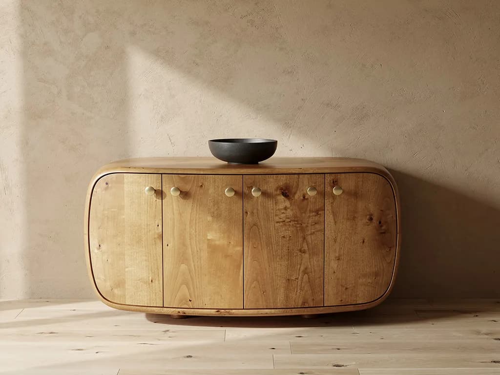 Gerundetes Sideboard aus hellem Massivholz mit Messingknöpfen vor sandfarbener Putzwand