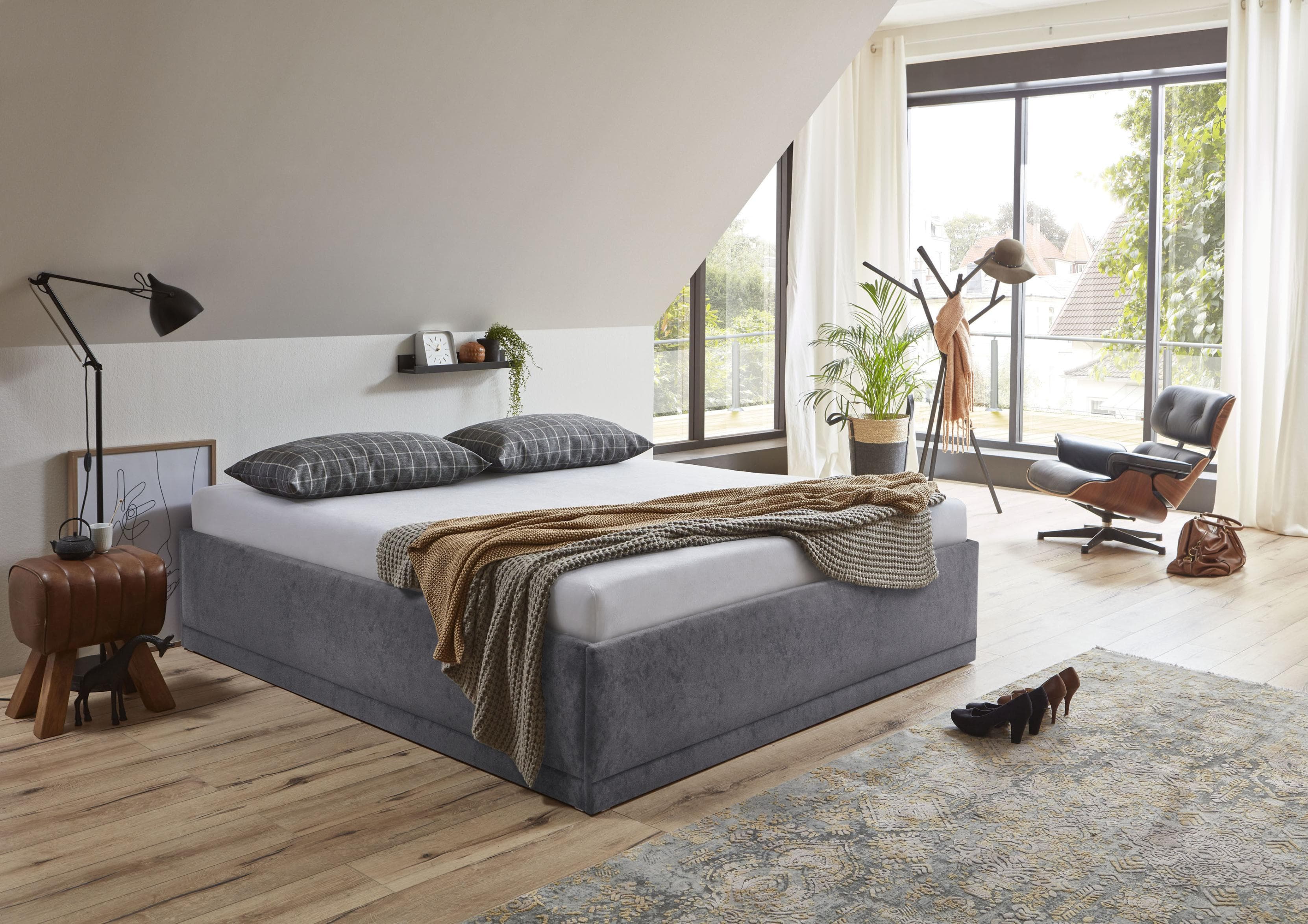 Komfortables Polsterbett mit Zierkissen und Bettkasten