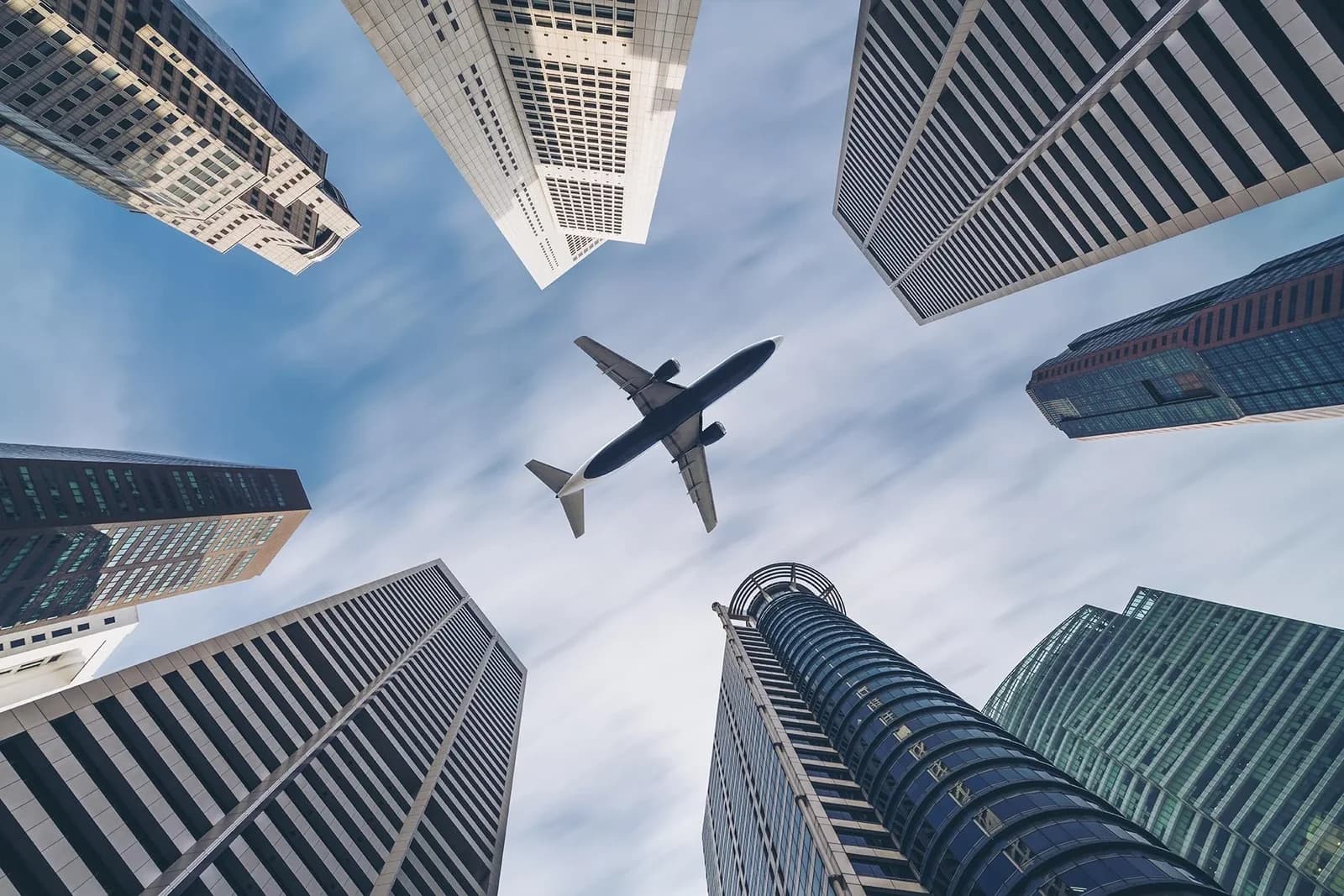 QUEENCE Acrylglasbild Flugzeug über Hochhäusern Blau Grau 3D Optik