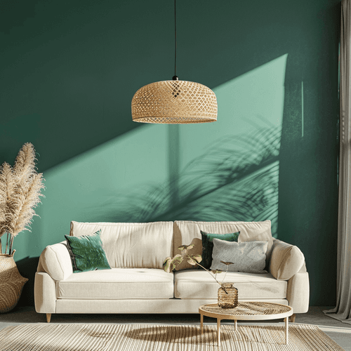 Helles Wohnzimmer mit beige Bouclé-Sofa, grünen Samtkissen, runder Rattan-Couchtisch und geflochtener Rattan-Pendelleuchte; Smaragdgrüne Wand wirft Palmenschatten, links Pampasgras im Korb.